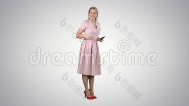 笑着站在<strong>渐变背景</strong>上穿着粉红色裙子的漂亮年轻女人。